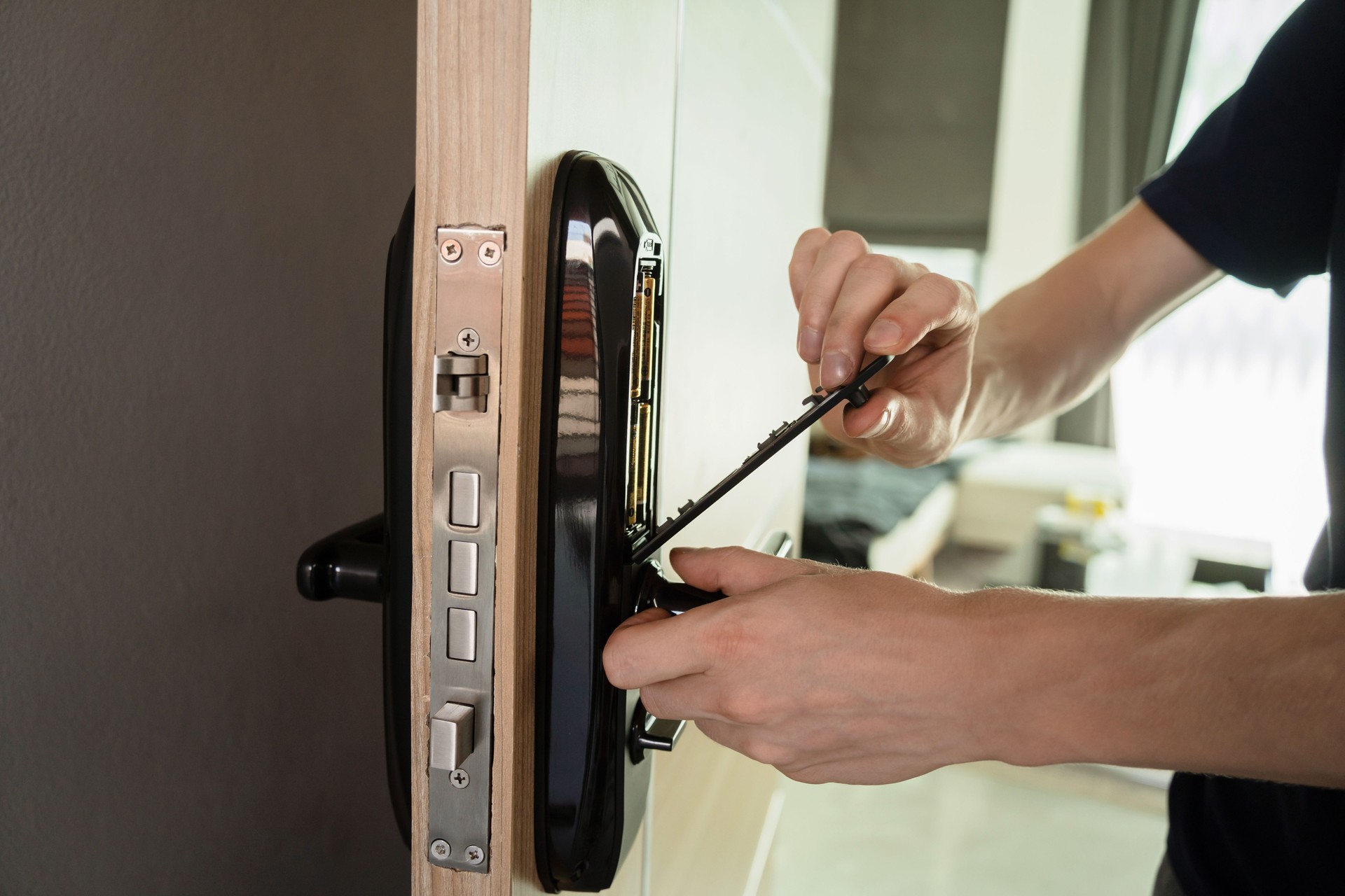 A technician installs a modern smart door lock on the wood door