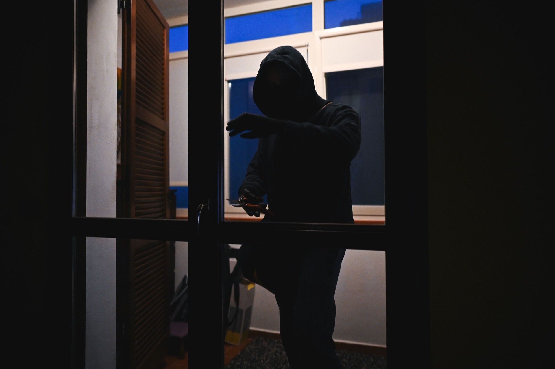 Masked burglar breaking into a house at night
